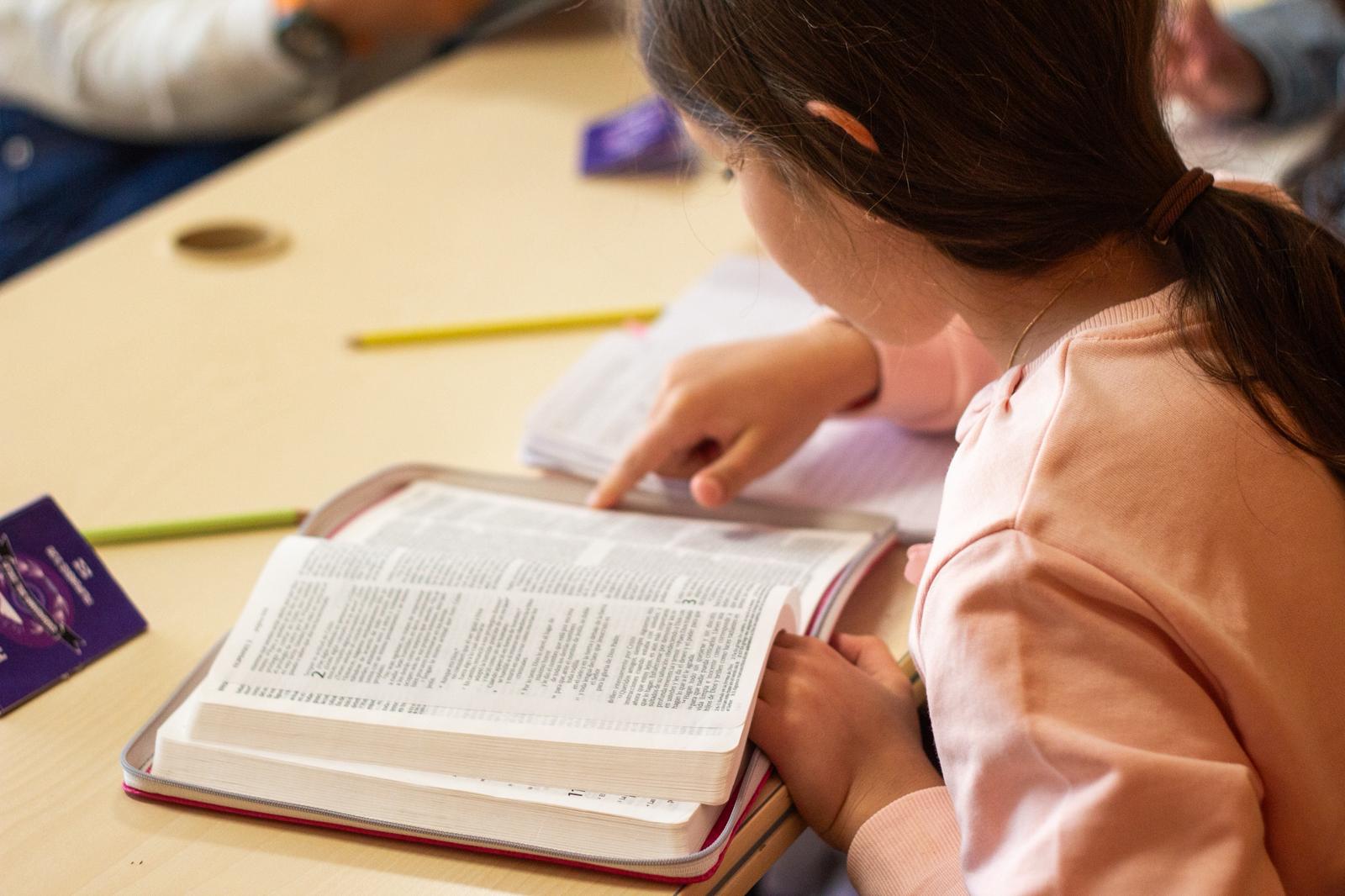 Niña leyendo la Biblia durante la clase