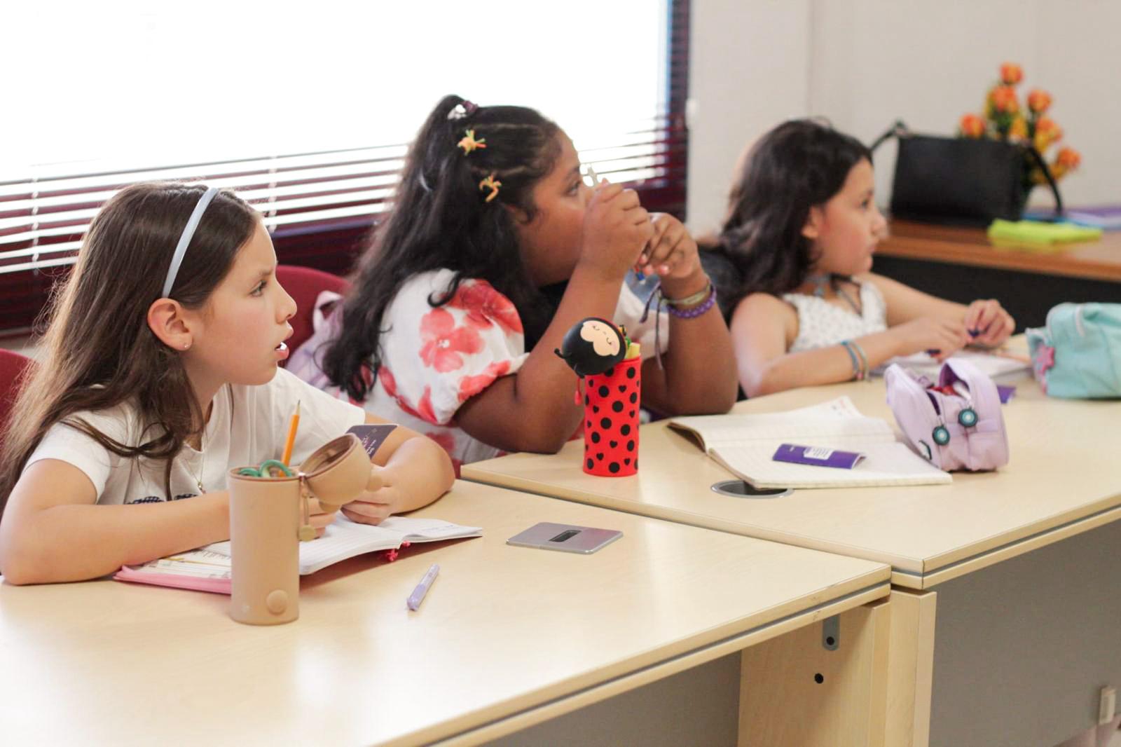 Niñas participando en clase con sus Biblias y cuadernos