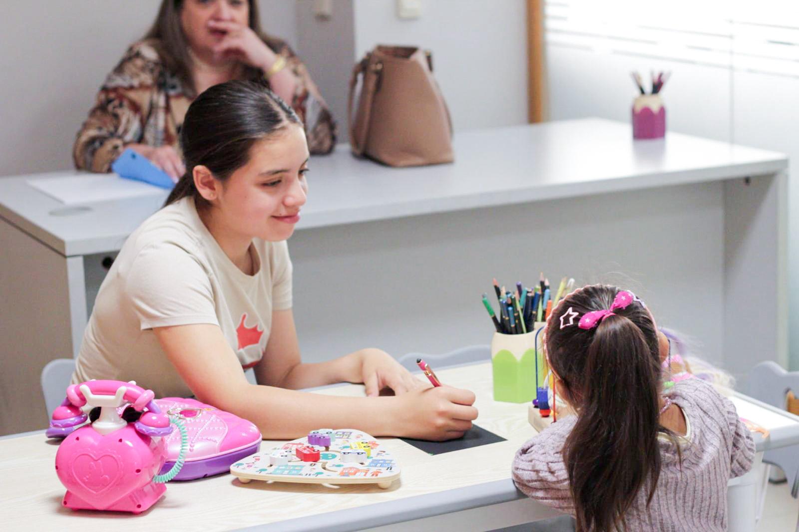 Maestra acompañando a una niña en actividad creativa